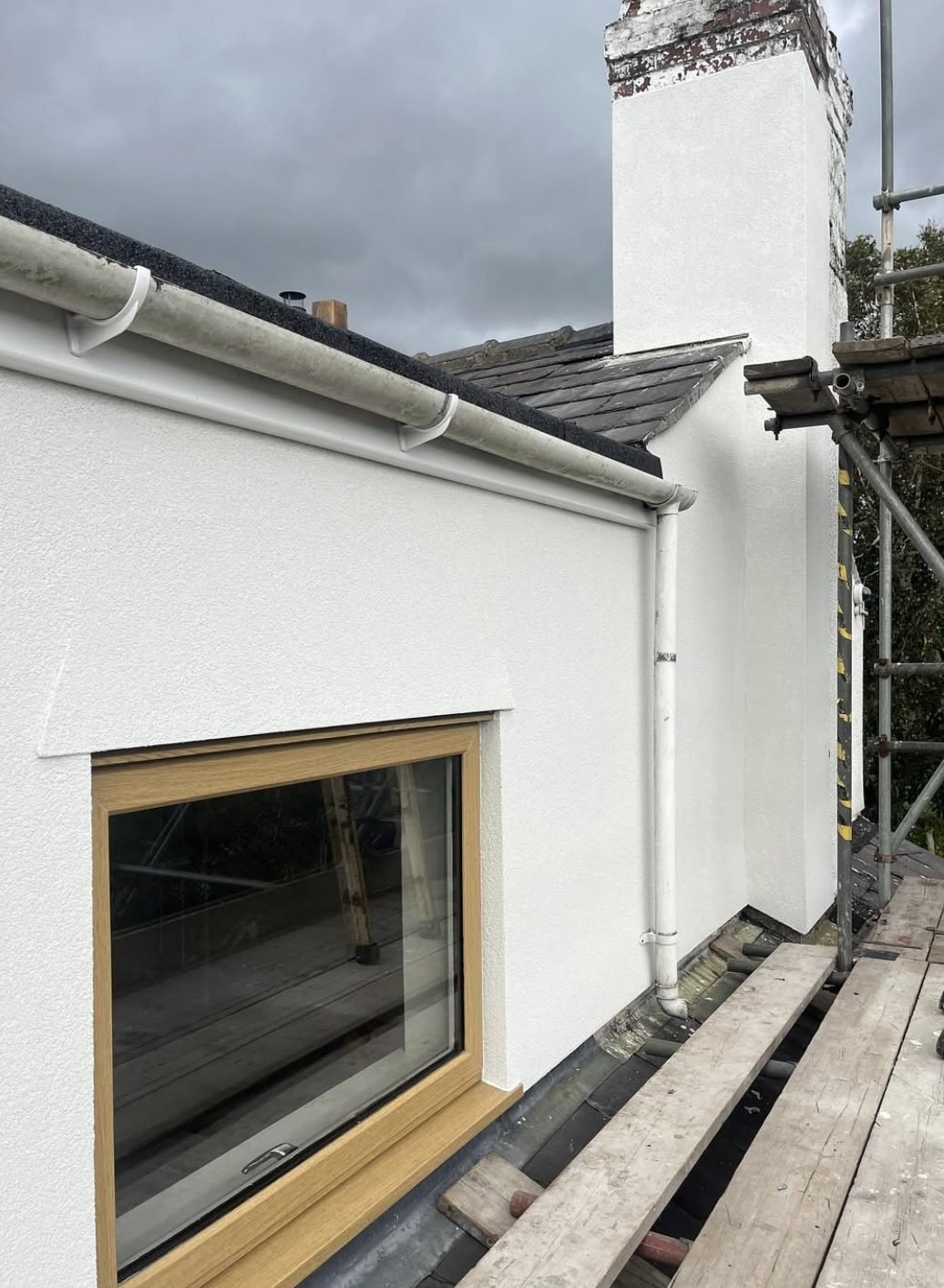 Rendered chimney stack and dormer side seen from scaffold boards