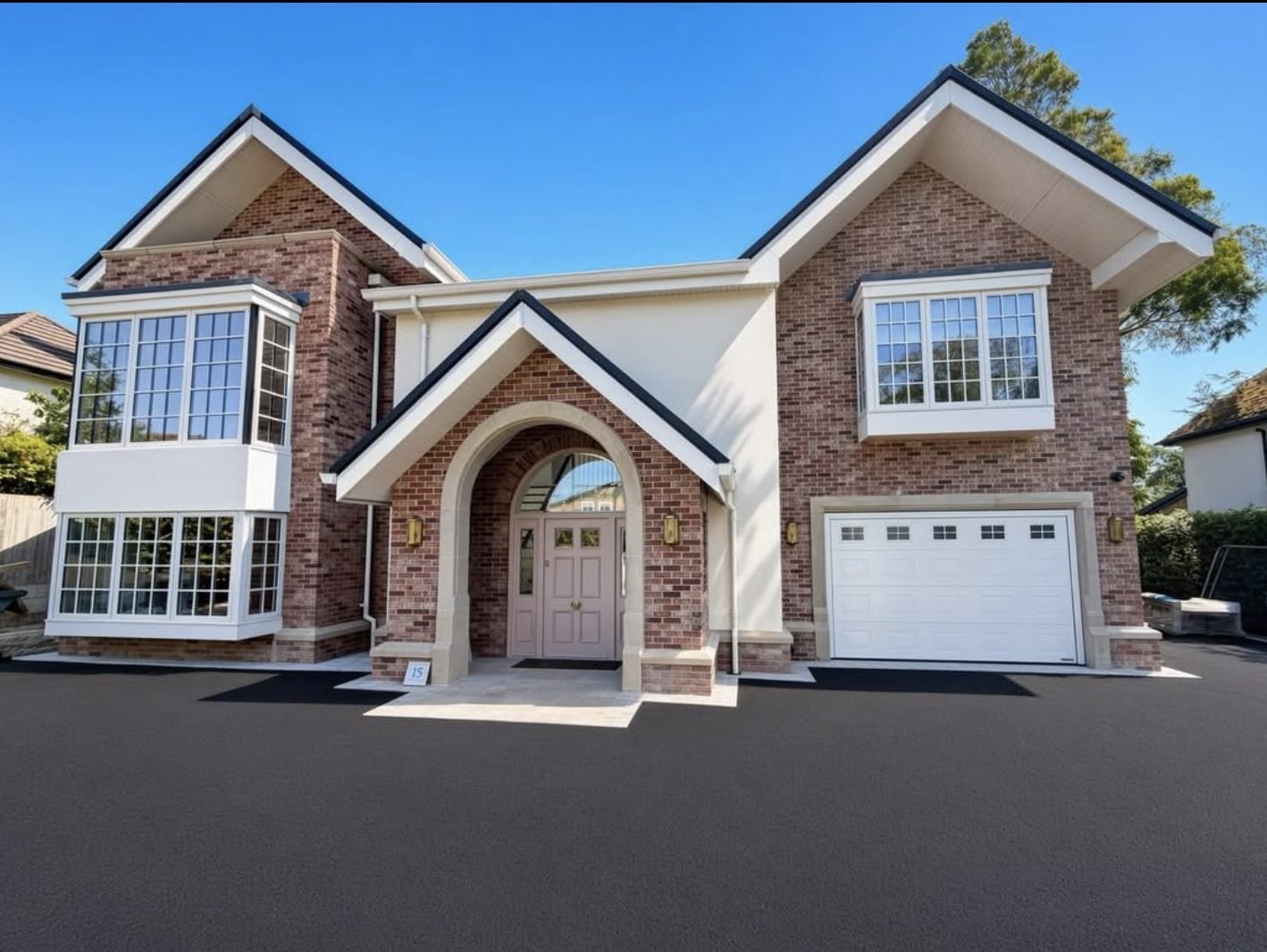 New house with cream render panels set between red brick gables