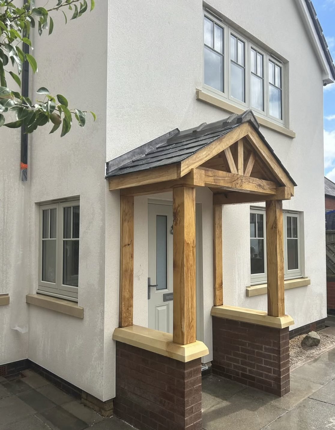 Cream rendered house front with an oak-framed porch on brick piers