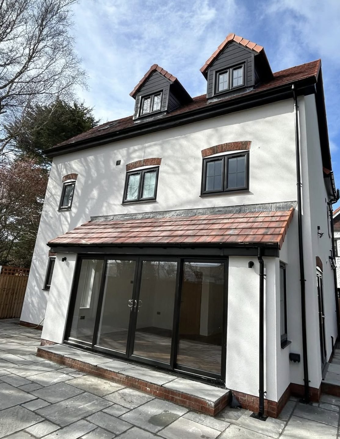 Three-storey back wall in white render with dormers and a single-storey extension